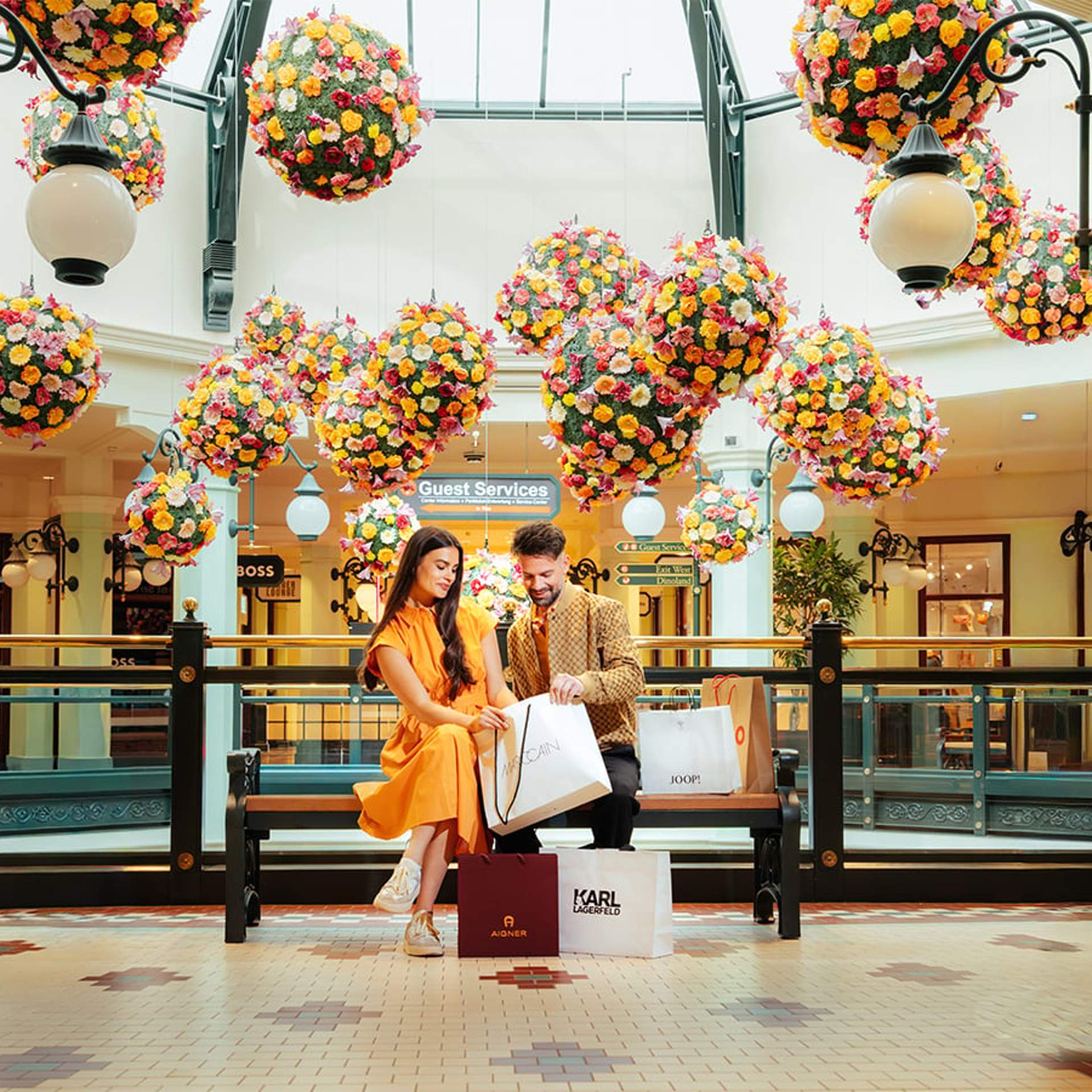 Helles Shopping Ambiente im Designer Outlet Salzburg mit Blumen und Gästen
